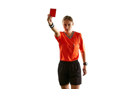 Serious young woman, football referee in uniform showing red card as dismissal symbol against white...