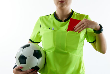 Young woman, female soccer referee holding ball, stopping game and showing red card against white studio backgroundの写真素材