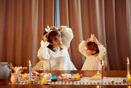 Happiness. Smiling mother making gingerbread with her little daughter, playing and having fun at home. Bunny ears, Easter symbolの写真素材