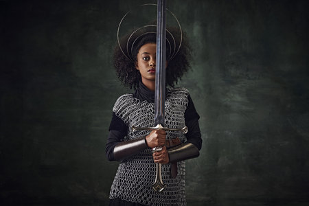Brave young African woman, medieval warrior in chainmail armor with halo-like rings above head...