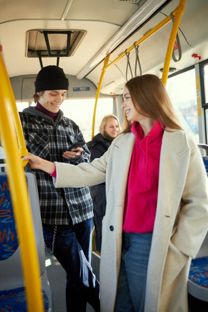 Young people standing in public transport, tram, bus. Easy of access to urban transport. Convenient city movementsの写真素材