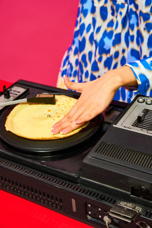 Young stylish woman, dj using sound mixer with pancake instead of vinyl record on pink background. Creative music poster. Partyの写真素材