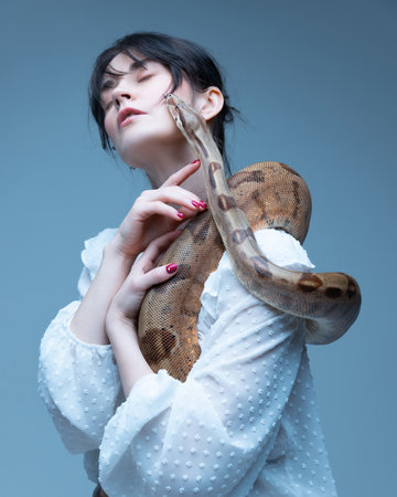 Wildlife protection promotional poster. Beautiful young woman in write blouse holding snake around...