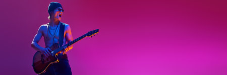 Emotional shirtless young man in sunglasses and hat playing electric guitar against pink background in neon lightの写真素材