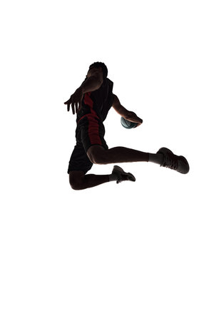 Spirit of competitive sports. Silhouette of basketball player in motion with ball during jump...