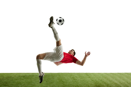 Determined young man, football player in motions during game, training, hitting ball and falling down isolated on white backgroundの写真素材