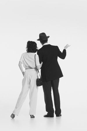 Man and woman in retro-style elegant costumes standing and looking somewhere with attention isolated on white background. Black and whiteの写真素材