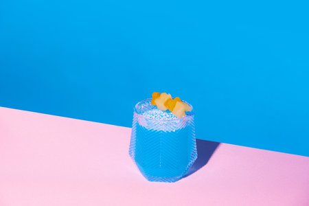 Sweet and sour blue tropical cocktail with pineapple slice against pink blue background. Refreshmentの写真素材