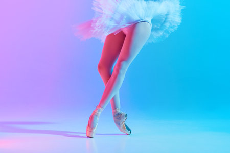 Cropped photo of young, slim ballet dancer in white tutu and pointe in neon light against vivid gradient background.の写真素材