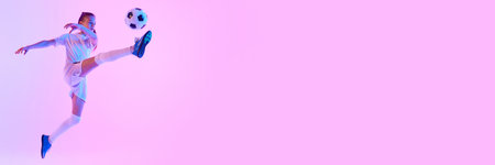 Dynamic image of teen girl, soccer player in motion kicking ball against pink studio background in neon lightの写真素材