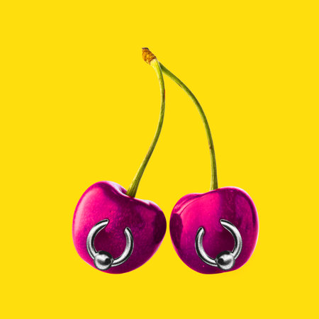 Two cherries with piercings against bright yellow background. Contemporary art collage.の写真素材