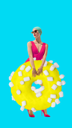 Young woman in pink swimsuit with yellow donut covered in marshmallows against bright blue...