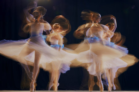 Young ballet ensemble in sheer dresses creating illusion of multiple movements against a dark background on stage.の写真素材