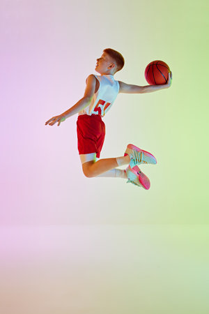 Side view full-length image of boy, basketball player during game in motion, practicing, throwing...