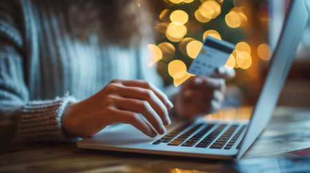 Person engaged in online shopping, holding credit card and using laptop for online purchases....