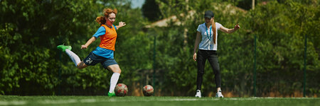 Focused Soccer Training. Young female soccer player practicing dribbling under the guidance of coach. Banner image.の写真素材
