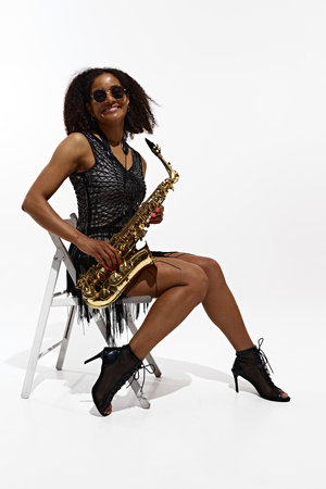 Jazz Diva. Portrait of artistic and talented young girl, musician performing with saxophone isolated on white backgroundの写真素材