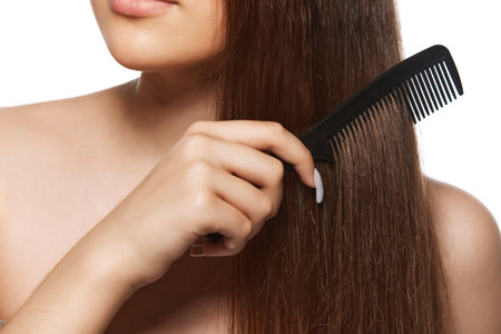 Cropped image of brunette straight female hair, girl brushing hair with brush isolated on white backgroundの写真素材