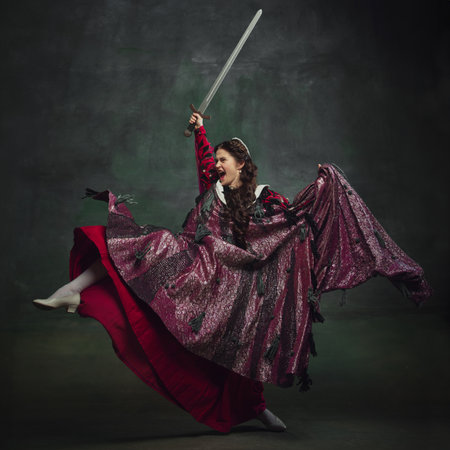 Powerful female warrior. Young emotional woman, royal person in dynamic pose with sword, showing...