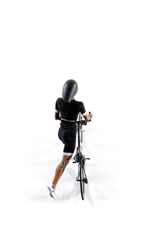 Cyclist in black outfit and helmet, sportive woman standing with modern bike isolated on white...