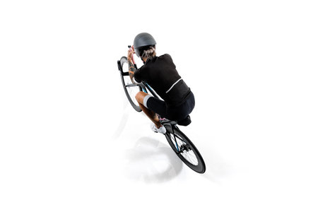 Female athlete in black sportswear and helmet, seen from above, riding a road bike in aerodynamic posture isolated on white background.の写真素材