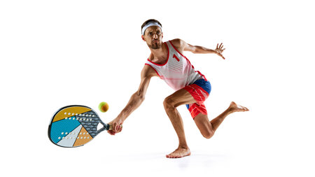 Young focused man, beach tennis player with colorful racket, playing isolated on white backgroundの写真素材