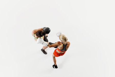 Top view of two competitive and focused women, boxing athletes in motion, fighting, training isolated on white backgroundの写真素材