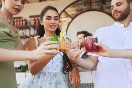 Friends , men and women gathering at trendy bar, toasting with vibrant cocktails and sharing good time together.の写真素材