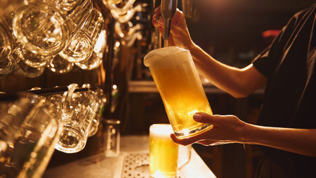 Female bartender pouring lager foamy beer from tap into glass. Organic drinks.