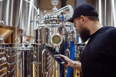 Concentrated man, technologist examining brewing equipment, maintaining thigh standards necessary...