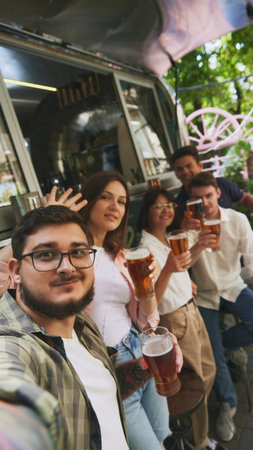 Selfie. Positive young people, men and women, friends meeting in warm evening at local outdoor bar, drinking beer and having relaxing momentsの写真素材