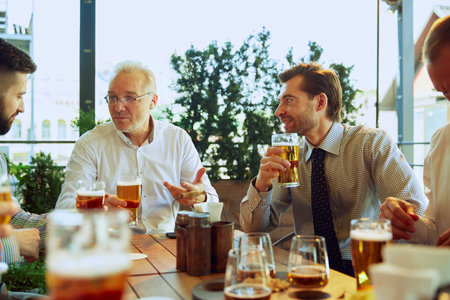 Businessmen gathering at outdoor pub,drinking lager beer, discussing their latest projects, blending work with relaxation.の写真素材