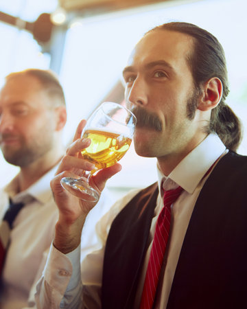 Focus on man in formal wear, with moustaches drinking lager beer at local outdoor pub. Meeting with colleagues after workの写真素材