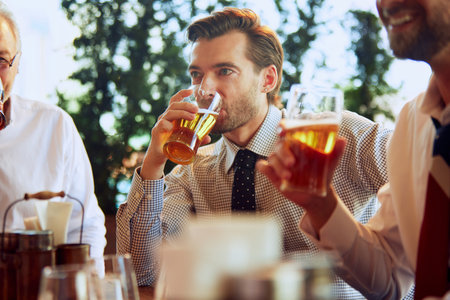Group of businesspeople, colleagues meeting at local pub, drinking beer, relaxing, talking. Teamwork and partnershipの写真素材
