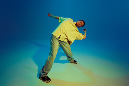 Lost in the music. Dynamic image for young man, hip-hop dancer making energetic performance against...