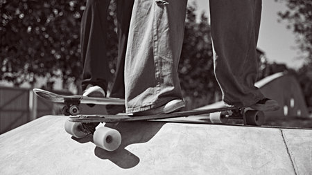 Focus on male legs in sneakers and pants in mouth on skateboard, training outdoors in city park....