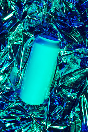 Aluminum can, on vibrant backdrop of holographic foil, creating visually striking image of refreshing beverage. Beer, soda water, lemonade, energy drinks.の写真素材