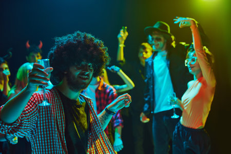 Friends in various Halloween costumes gathering at nightclub for cheerful and energetic celebration....