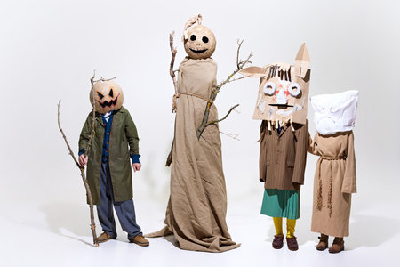 Group of people wearing eerie masks and oversized robes. Giant pumpkin head, twig branches, and...