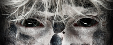 Close-up of demonic dark eyes with person face partially painted in a monochromatic palette, suggesting sense of fear and supernaturalの写真素材