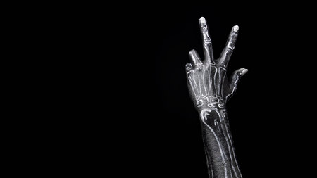 Human hand painted as skeleton gesturing against black background. Image suitable for web ads,...