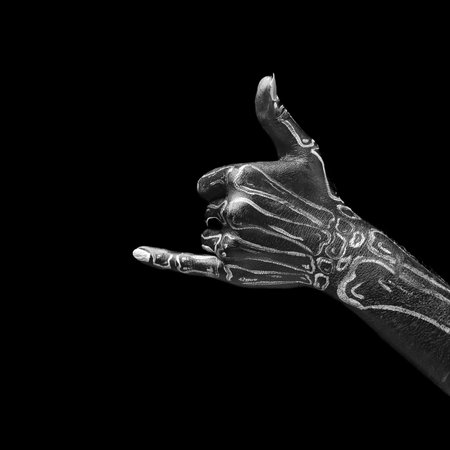 Skeleton hand making hang loose sign against black background. Halloween party invitation templateの写真素材