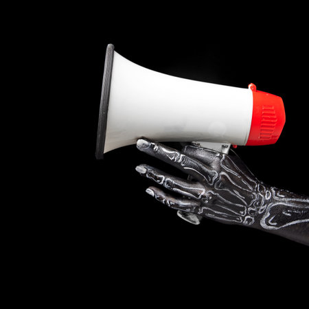 Person hand in skeleton drawings holding megaphone against black background. Promotion of news,...