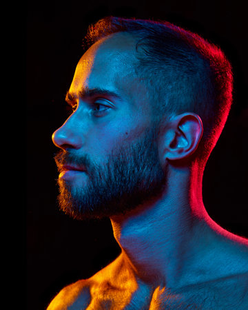 Side view portrait of handsome bearded man with spotless, well-kept skin and short haircut posing...