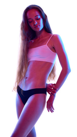 Beautiful young woman with long hair, slim, beautiful body, posing in underwear isolated on white studio background in neon lightの写真素材