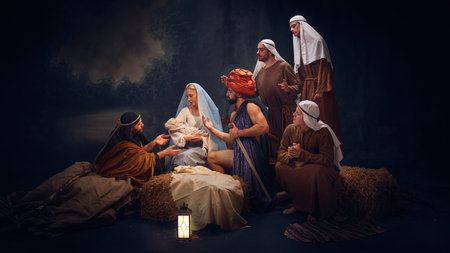 Nativity scene with Mary holding baby Jesus, surrounded by wise men, shepherds, each offering gestures of adoration and reverence.の写真素材