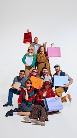 Crowd of people forming a human tower, showing their excitement about shopping, holding many colorful shopping bagsの写真素材
