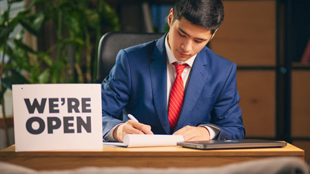 Businessman sitting at table with we are open sign and signing documents. Contract signing