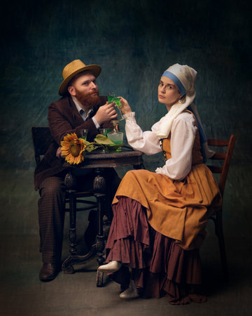 Cinematic portrait of man and woman sitting and drinking alcohol drinks over dark vintage, medieval backgroundの写真素材