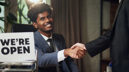 Businessman shaking hands after closing deal with we are open sign on his desk.の写真素材